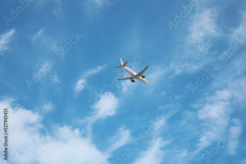 Modern airplane flying in blue sky low angle view