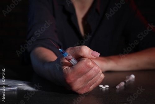 Drug addicted woman with syringe at table  closeup