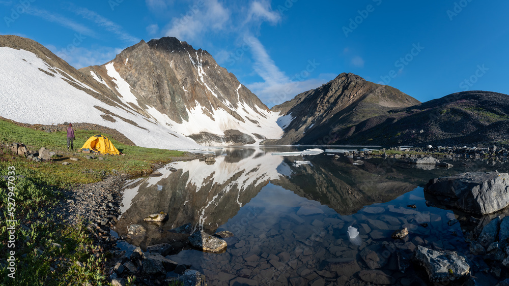 Mountains views in northern Canada during summer time with calm lake and mountain reflection in the water below. 