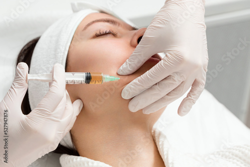 Papier peint Cosmetologist gives an injection into the cheekbones of a young woman