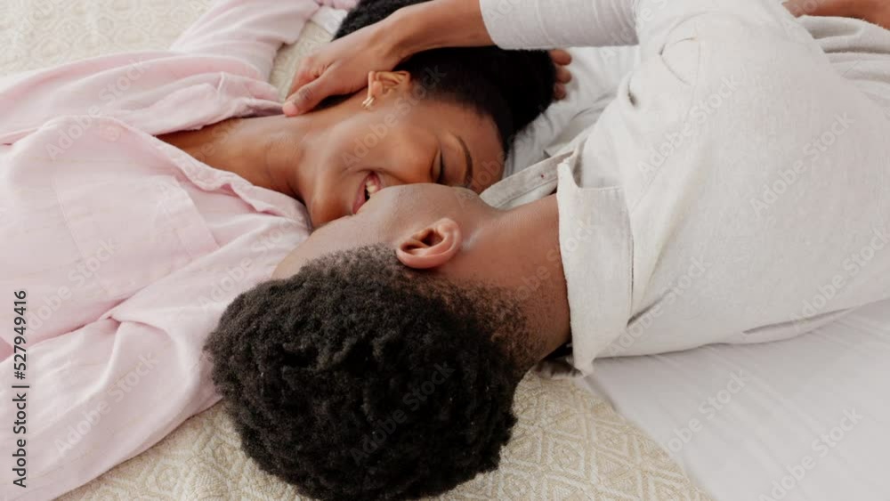 Happy, love and couple in a bedroom kiss and laughing in happiness, bonding time together at home. Young black man and woman kissing while lying on a bed with a smile in joy for caring relationship. Happy, love and couple in a bedroom kiss and laughing in happiness, bonding time together at home. Young black man and woman kissing while lying on a bed with a smile in joy for caring relationship.