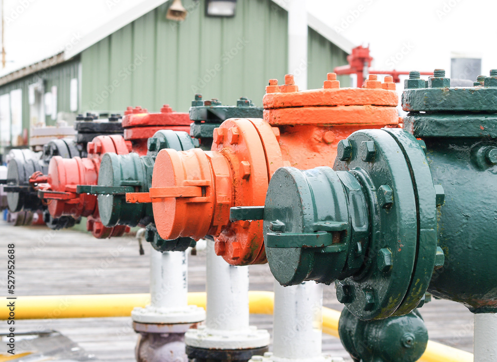 Industrial Flow valves in different colors in line on wharf