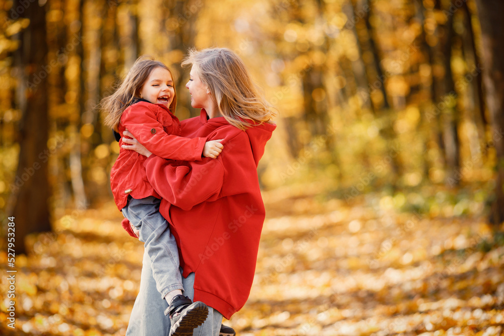 Mother and daughter walking and playing in autumn forest