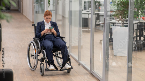 Caucasian woman using mobile phone in wheelchair at office.  © Михаил Решетников