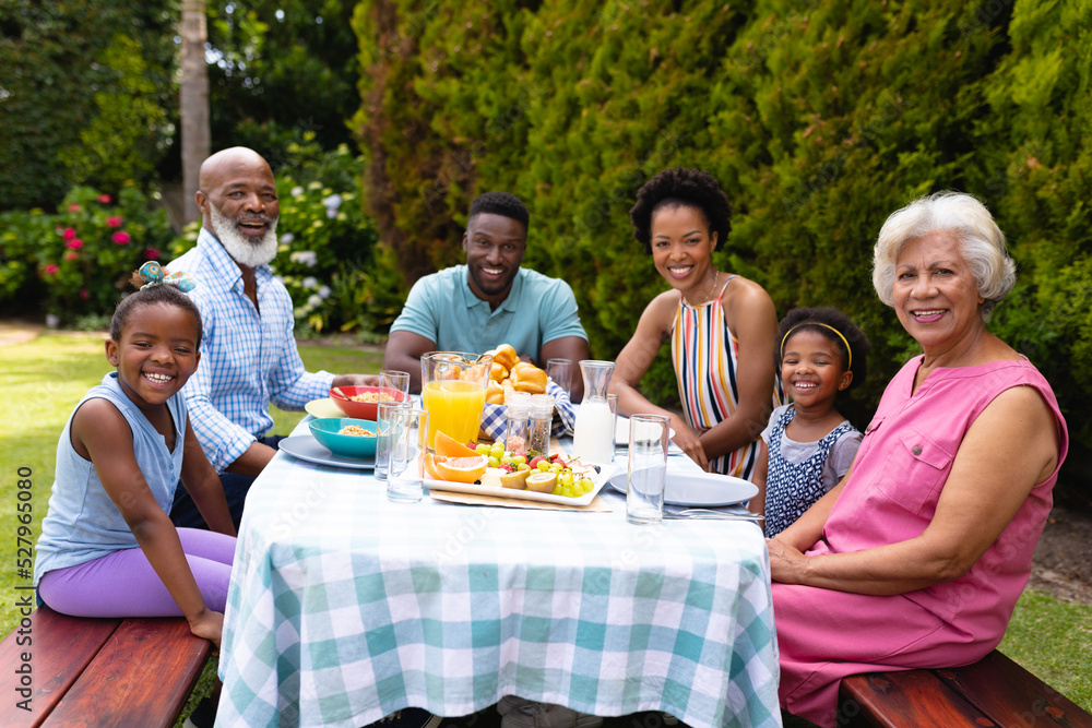 Portrait of smiling multiracial family sitting at breakfast table in backyard Portrait of smiling multiracial family sitting at breakfast table in backyard