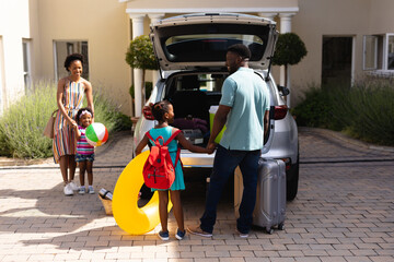 Happy african american family loading luggage in car trunk while going for picnic