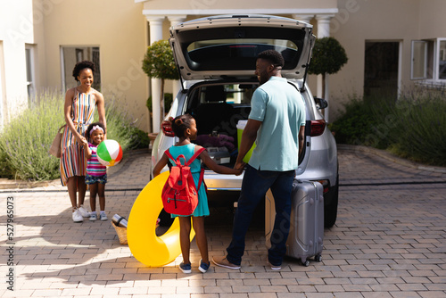 Happy african american family loading luggage in car trunk while going for picnic