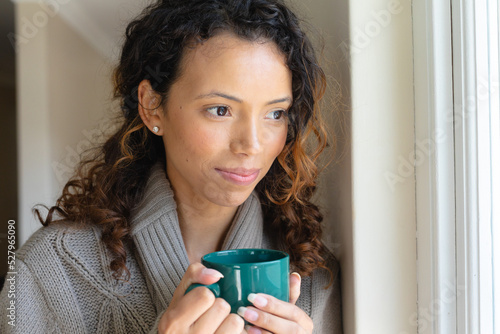 Close up of a african american woman holding coffee cup while looking out of the window