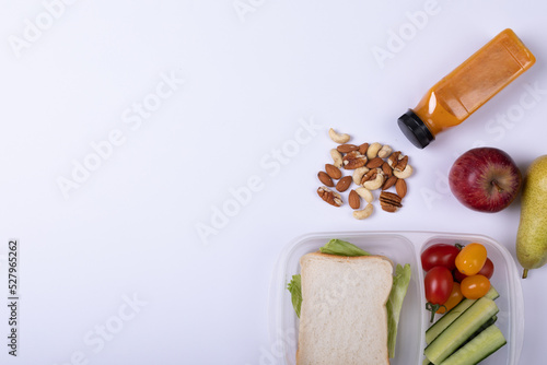 Directly above shot of healthy food and tiffin box by juice bottle over white background, copy space