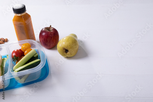 Fruits, juice bottle and lunch box with copy space on grey background