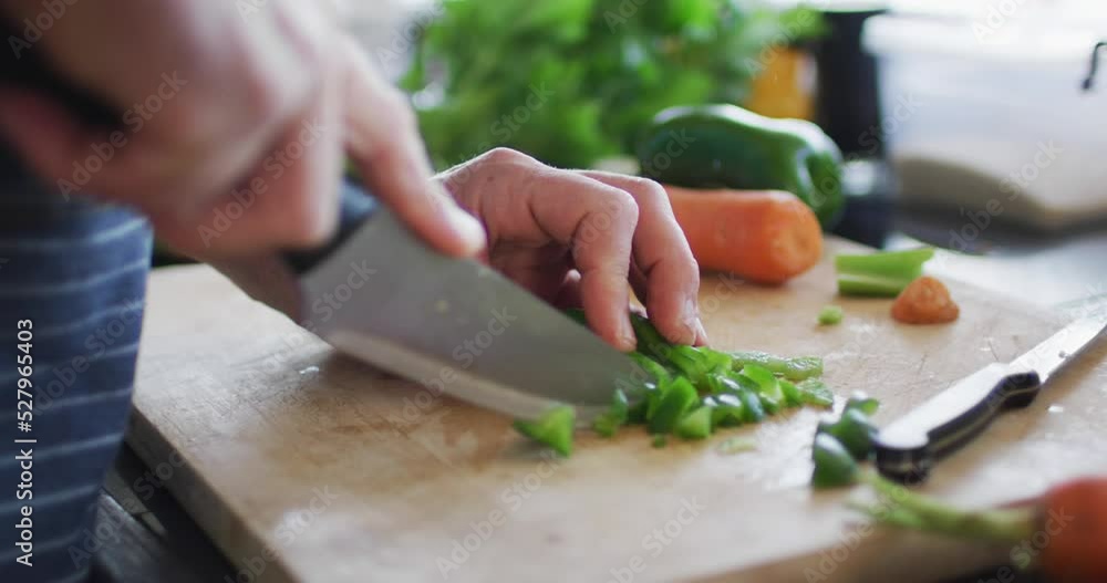 Closeup of mans hand cutting green pepper on the cutting board Closeup of mans hand cutting green pepper on the cutting board