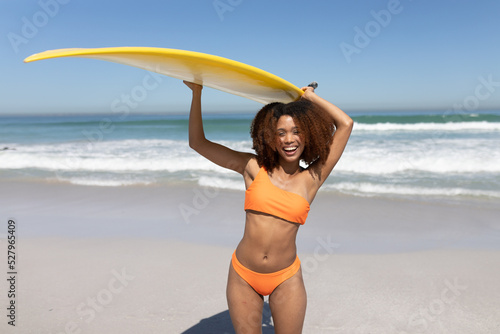Mixed race woman holding a surfboard  on the beach