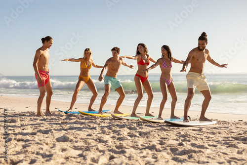 Multi-ethnic group of male and female, surfing on the beach