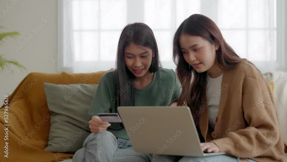 Two asian young woman happy smiling and using computer laptop on couch in living room at home Two asian young woman happy smiling and using computer laptop on couch in living room at home