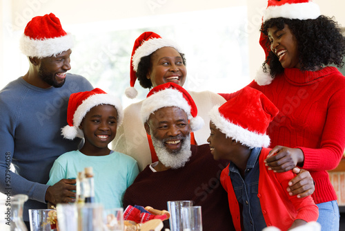 Multi generation african american family smiling and wearing santa hats