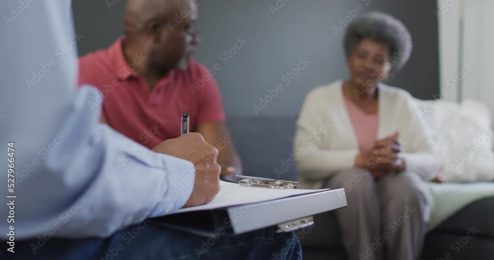 Mixed race senior male counsellor with clipboard advising to group of diverse senior friends Mixed race senior male counsellor with clipboard advising to group of diverse senior friends