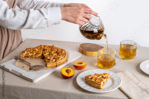 Woman  pouring herbal tea. Homemade apple pie on cutting board on a family table. Autumn baking © svetlana_nsk