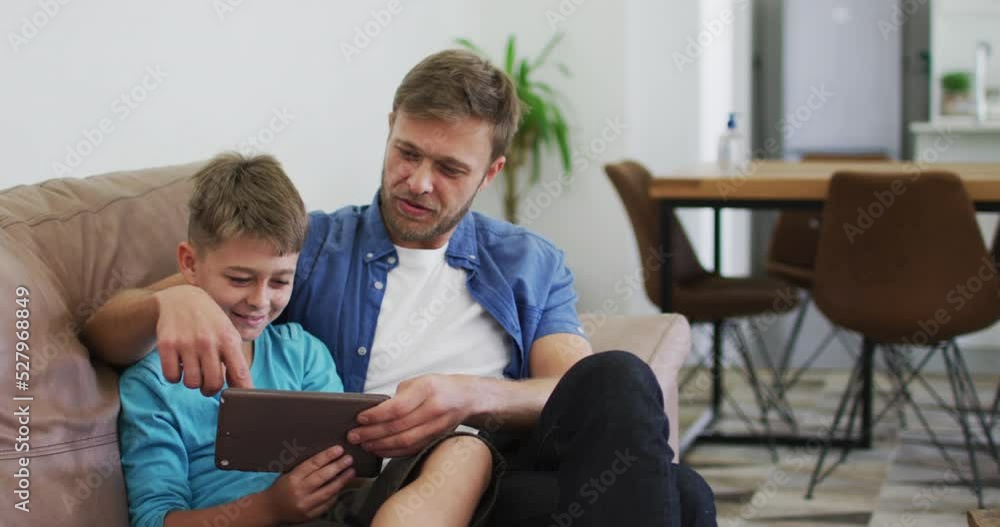 Caucasian man and his son using digital tablet and laughing Caucasian man and his son using digital tablet and laughing