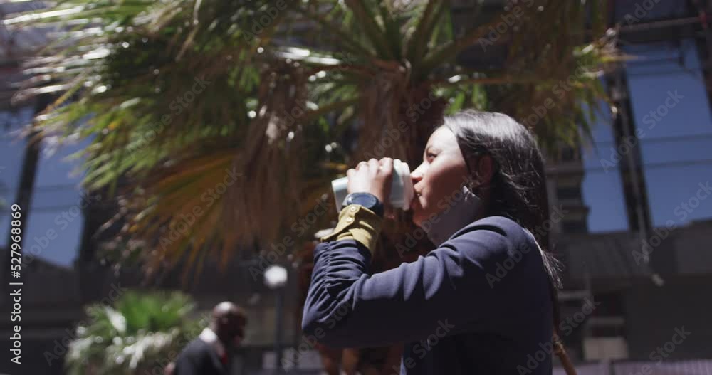 African american woman wearing face mask drinking coffee in city park African american woman wearing face mask drinking coffee in city park