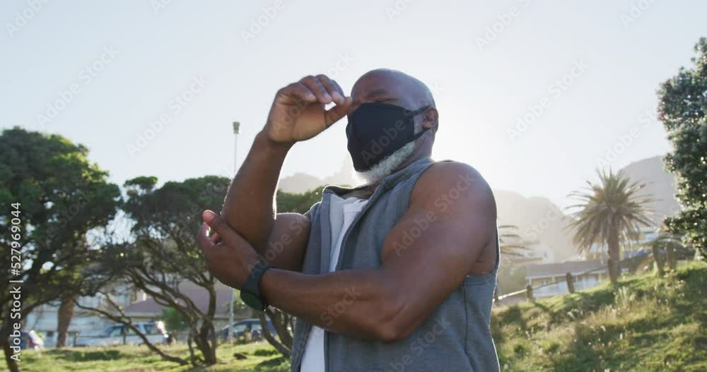 Senior african american man wearing face mask exercising stretching in countryside Senior african american man wearing face mask exercising stretching in countryside