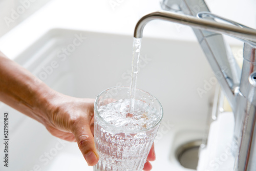 浄水器の水をグラスに満たす主婦の手元 photo