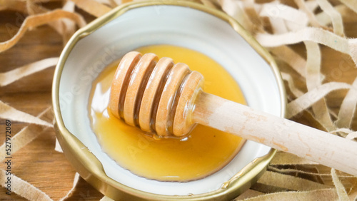 Honey dipper surrounded by honey on wood background. Health and beauty product sustainable lifestyle concept.