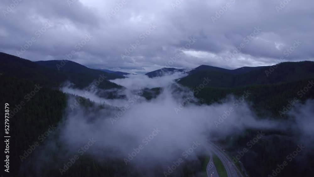 Aerial view of highway in mountain during sunset with fog. Tranquility mountain place. Cars and trucks is going on highway during a rainy weather in mountain. Aerial view of highway in mountain during sunset with fog. Tranquility mountain place. Cars and trucks is going on highway during a rainy weather in mountain.