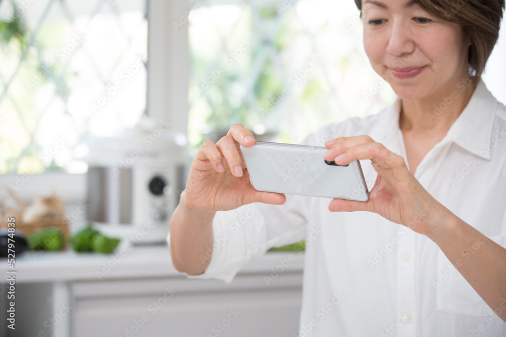 ダイニングキッチンでスマホで撮影するミドルの主婦 ダイニングキッチンでスマホで撮影するミドルの主婦