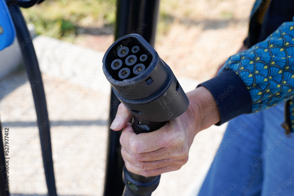 woman holding a DC - CCS combo type 2 EV charging connector at electric ...