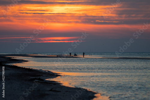 autumn sunset at the beach with fisherman