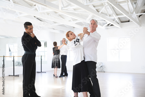 Mixed race dance teacher helping his ballroom dancing class