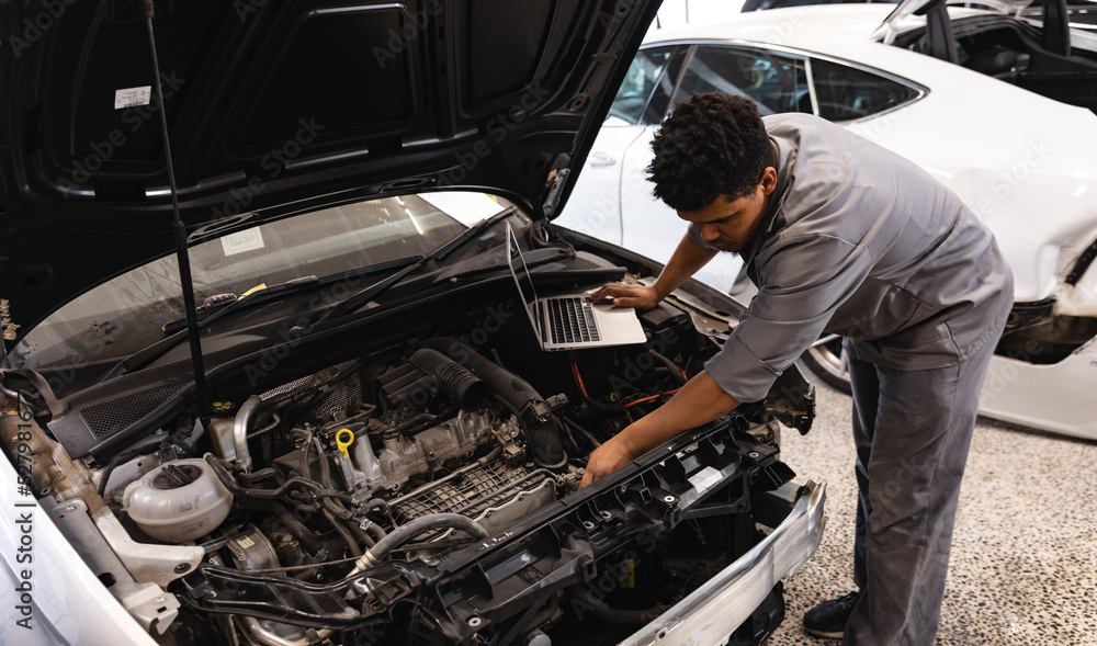 Mixed race mechanic man inspecting car motor Mixed race mechanic man inspecting car motor
