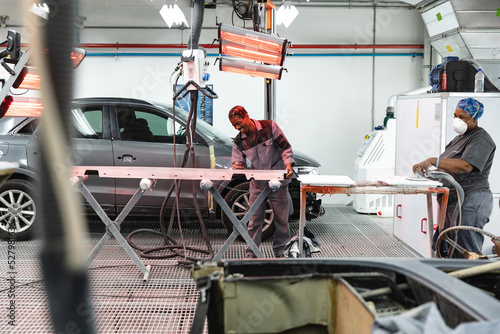 Happy multi races mechanics sanding and drying car pieces photo