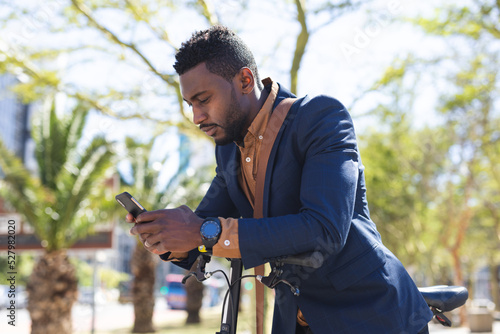 African american man sitting on a bicycle using a smartphone