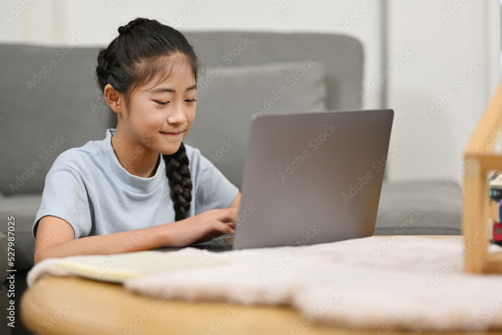 Happy Asian preteen girl school distance learning online at virtual class with teacher tutor on laptop by video conference call, watching online lesson at home. Happy Asian preteen girl school distance learning online at virtual class with teacher tutor on laptop by video conference call, watching online lesson at home.