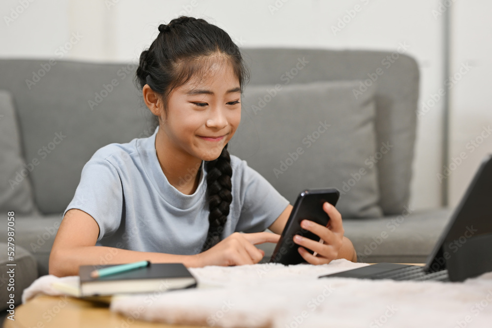 Asian little school girl using tablet and smartphone for studying online classes at home, Online learning, E-learning, Distance learning, online education concept. Asian little school girl using tablet and smartphone for studying online classes at home, Online learning, E-learning, Distance learning, online education concept.