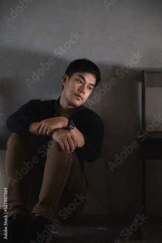 Sad and depressed young male sitting on the floor in the room, sad mood,feel tired, lonely and unhappy concept. Selective focus.