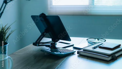 Stylish workplace with telephone and tablet PC on table in home office, beautiful blue fillter