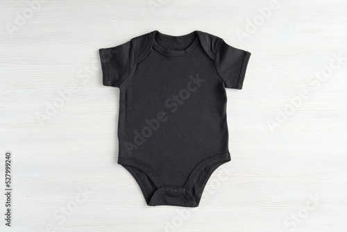 Black baby onesie bodysuit mockup for design presentation, minimal template on white wooden background. photo
