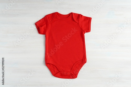 Red baby onesie bodysuit mockup for design presentation, minimal template on white wooden background. photo
