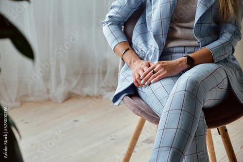 Hands of an unrecognizable woman in a suit sitting on a chair