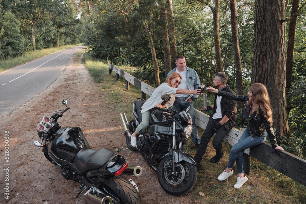 A company of friends travel together on motorcycles, stopped at the roadside, have fun and drink tea A company of friends travel together on motorcycles, stopped at the roadside, have fun and drink tea