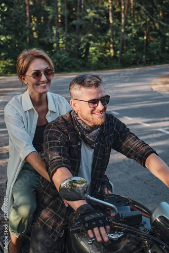 Middle age couple riding a motorcycle, traveling together on a forest road