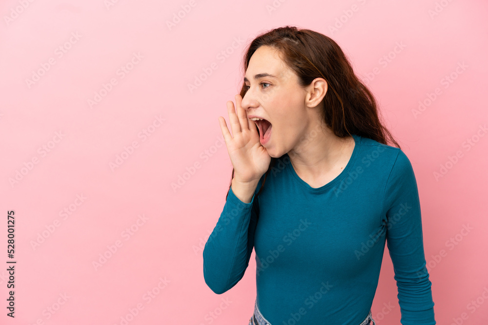 Young caucasian woman isolated on pink background shouting with mouth wide open to the side Young caucasian woman isolated on pink background shouting with mouth wide open to the side