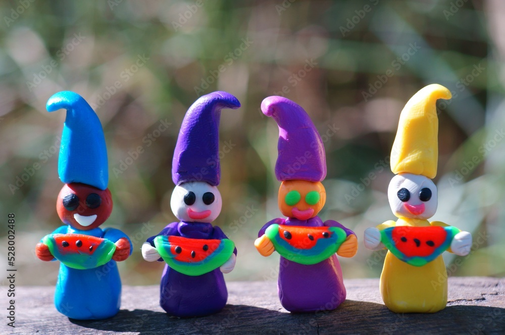 Figures of colorful dwarfs hold watermelons in their hands and smile. Positive mood. The emotion of joy.