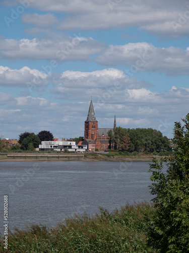 vertical landscape photo with the river Scheldt and a view of the Sint Martinuskerk in Zwijndrecht, Belgium photo
