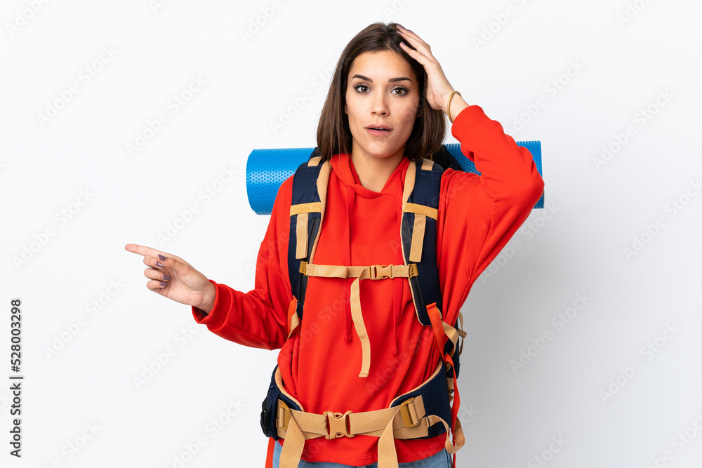 Young caucasian mountaineer girl with a big backpack isolated on white background surprised and pointing finger to the side Young caucasian mountaineer girl with a big backpack isolated on white background surprised and pointing finger to the side