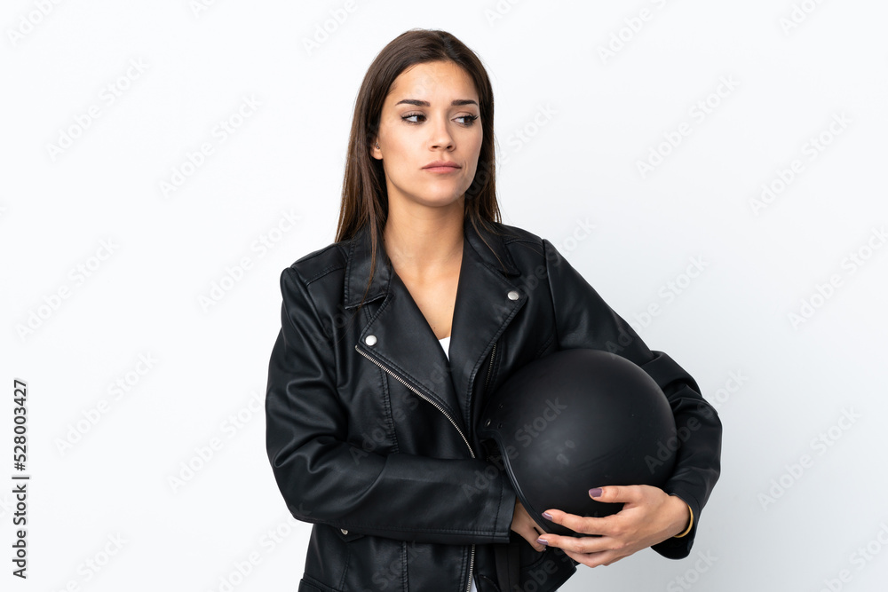 Caucasian girl holding a motorcycle helmet on white background thinking an idea Caucasian girl holding a motorcycle helmet on white background thinking an idea