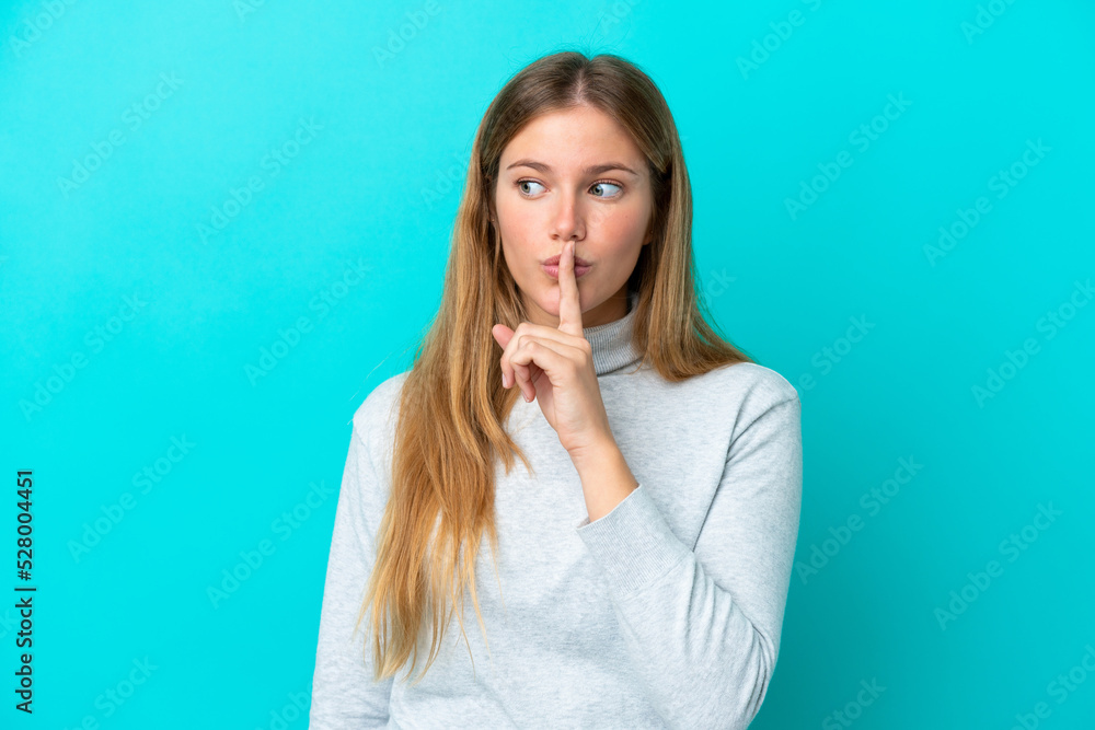 Young blonde woman isolated on blue background showing a sign of silence gesture putting finger in mouth Young blonde woman isolated on blue background showing a sign of silence gesture putting finger in mouth
