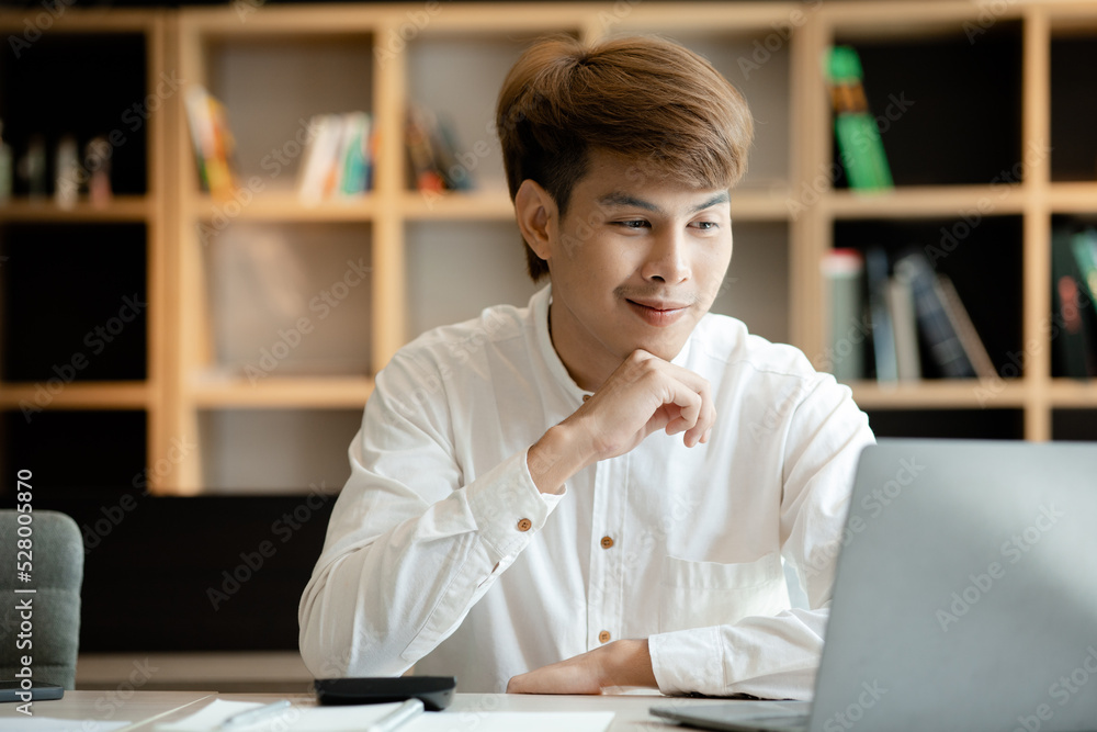 A man sits in the office of a startup company, he is an employee working in the marketing department, planning marketing to grow the company. Concept of working in a startup company office. A man sits in the office of a startup company, he is an employee working in the marketing department, planning marketing to grow the company. Concept of working in a startup company office.